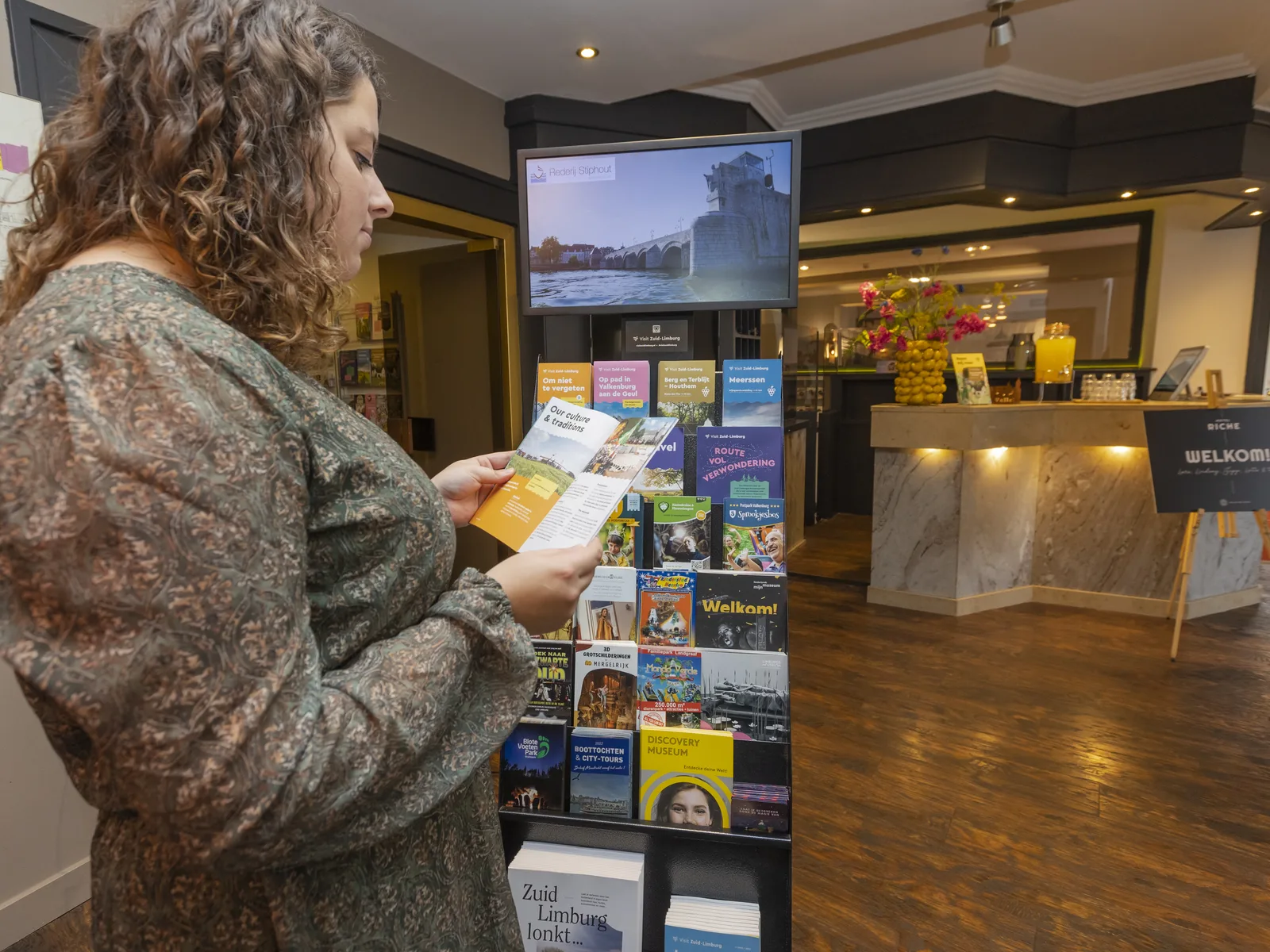 Gast leest een folder bij de folderdisplay met digitaal scherm